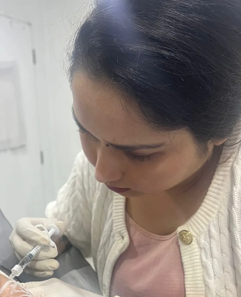 Dr. Pooja Shrivastava administering an injectable treatment to a patient's forehead.
